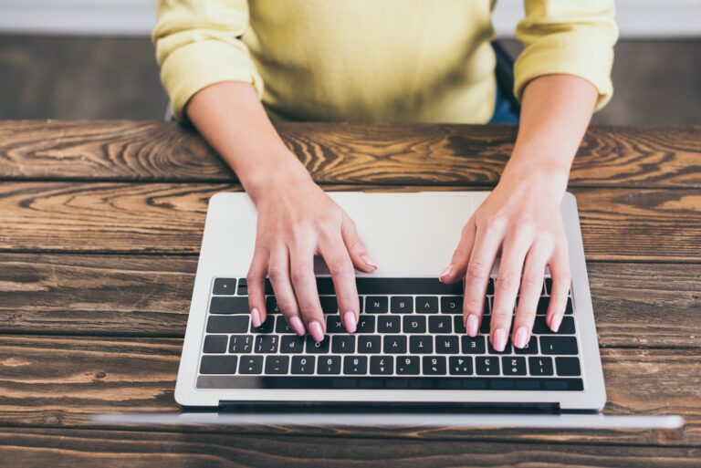 cropped view of female writer typing on laptop at home